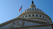 Low angle view of the historic landmkark, the Capitol building in Washington DC, flag flying, a dome and statue.