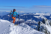 Woman on ski tour ascending to Kellerjoch, Kaiser Mountains in background, Kellerjoch, Zillertal, Hochfügen, Tux Alps, Tyrol, Austria