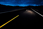 Empty highway at night with car headlights