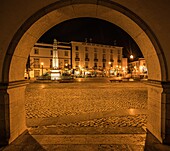 Praca República in the evening with restaurant in lantern light seen through an arcade of the town hall, Tavira, Algarve, Portugal