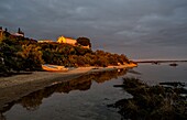 Ruderboot am Strand und Kirche des denkmalgeschützten Dorfs Cacela Velha im Abendlicht, Algarve, Portugal