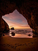 View through a rock gate in the light of dawn to the sea, Praia dos três Irmaos,