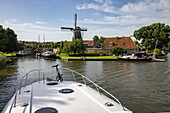Bow of Le Boat Elegance houseboat and De Kaai windmill, Sloten, Friesland, The Netherlands, Europe