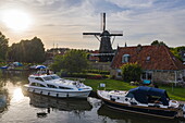 Luftaufnahme von Le Boat Elegance Hausboot am Stadtanleger vor Windmühle De Kaai bei Sonnenuntergang, Sloten, Friesland, Niederlande, Europa