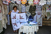 Frau präsentiert handgestickte Spitzentischdecke im Strickgeschäft, Szentendre, Pest, Ungarn, Europa