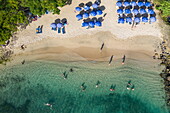 Luftaufnahme von Menschen im Wasser und Sonnenschirme am Strand von Pigeon Island National Landmark, Gros Islet Quarter, St. Lucia, Karibik