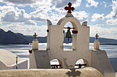 Bell tower of a Greek Orthodox Church with expedition cruise ship World Explorer (Nicko Cruises) in the distance, Oia, Santorini, South Aegean, Greece, Europe