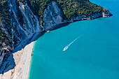 Aerial view of a boat in the turquoise waters approaching Myrtos Beach, near Assos, Kefalonia, Ionian Islands, Greece, Europe