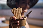 Detail of cup of ice cream with heart-shaped waffle in young woman&#39;s hands aboard expedition cruise ship World Voyager (Nicko Cruises), Caribbean Sea, near Nicaragua, Central America