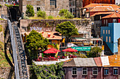 Idyllisch bunte Häuser und Gärten in Etagen neben der steil verlaufenden Standseilbahn Funicular dos Guindais in Porto, Portugal