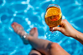 Aperol Spritz by the pool with feet in the water aboard expedition cruise ship World Voyager (Nicko Cruises), Pacific Ocean, near Panama, Central America