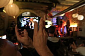 Jemand filmt mit Handy das Donnerstagskonzert im Café Olive, Boulevard Victor Hugo, Nimes, Gard, Okzitanien, Frankreich