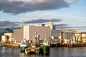 View of the herring oil factory with 2 ships in the foreground, Bodö; Nordland, Norway, Europe