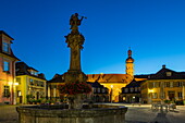 Statue am Brunnen und beleuchteter Turm von Schloss Weikersheim in der Abenddämmerung, Weikersheim, Franken, Baden-Württemberg, Deutschland, Europa