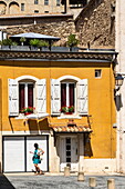 Frau läuft an einem gelben Haus in der Altstadt vorbei, Béziers, Hérault, Frankreich, Europa