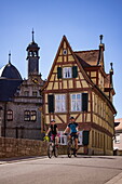 Two cyclists pass the Malerwinkelhaus in the old town, Marktbreit, Franconia, Bavaria, Germany, Europe