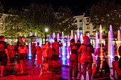Menschen bewundern nachts beleuchtete Brunnen, Béziers, Hérault, Okzitanien, Frankreich, Europa