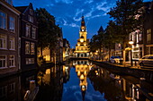 Reflection of the illuminated Waag building and Cheese Museum in a canal at dusk, Alkmaar, North Holland, The Netherlands, Europe