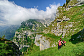 Zwei Personen wandern durch steile Grasflanke, Feltriner Berge, Belluneser Höhenweg, Dolomiten, Venezien, Venetien, Italien