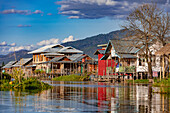 Colorful houses on stilts along the waterway through the town of Nang Pang in the shallow Inle Lake in Myanmar, Asia