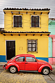 red VW Beetle parked in front of yellow blue house, San Cristóbal de las Casas, Central Highlands (Sierra Madre de Chiapas), Mexico, North America, Latin America