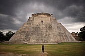 Frau steht vor Pyramide des Zauberers (Pirámide del Adivino), Archäologische Zone Uxmal, Maya Ruinenstadt, Yucatán, Mexiko, Zentralamerika, Nordamerika, Amerika