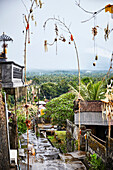 Straße nach Regen, gesäumt von Penjor-Dekorationen, zur Feier von Galungan und Kuningan in einem traditionellen Dorf in der Karangasem Region, Bali, Indonesien