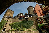 View through an arched portal to the main buildings of the Schönburg: gate tower, Barbarossa tower and hotel building, Oberwesel, Upper Middle Rhine Valley, Rhineland-Palatinate, Germany