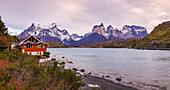 The hotel on Lake Pehoe as a panorama on the Torres del Paine massif in the early morning with dawn