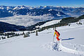 Woman on ski tour descending from Wiedersberger Horn, Tux Alps and Karwendel in background, Wiedersberger Horn, Kitzbühel Alps, Tyrol, Austria