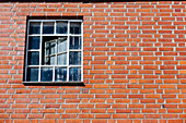 Nesbru, Norwegen, kleines quadratisches Fenster vor einer Backsteinmauer