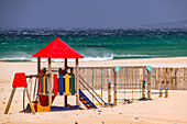 A colorful playground on the stormy sandy beach of Conil de la Frontera on the Andalusian Costa de la Luz, Spain