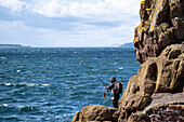 Blick auf eine Frau beim Angeln, Dunbar, East Lothian, Schottland, Vereinigtes Königreich