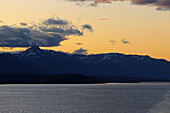 Argentien; Feuerland; Süd-Patagonien; Beagle Kanal auf argentinischer Seite; Blick auf die Berggipfel der Isla Navarino in Süd-Chile; dunkle Wolken am leuchtend gelben Abendhimmel
