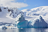Antarktis; antarktische Halbinsel bei Yalour Island; Schnee bedeckte Berge und Gletscher; leuchtend türkisfarbener Eisberg