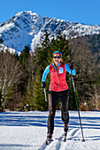 Woman cross-country skiing running through the Kloo-Aschertal, Bayrischzell, Mangfall Mountains, Bavarian Alps, Upper Bavaria, Bavaria, Germany