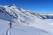 Woman on ski tour climbs to Roßkarscharte, Sichelkopf in the background, Zittau Hut, Hohe Tauern National Park, Zillertal Alps, Tyrol, Austria