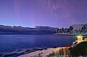 Beleuchteter Leuchtturm bei Tungeneset mit Sternhimmel, Teufelszähne und Ersfjord im Hintergrund, Okshornan, Tungeneset, Senja, Troms og Finnmark, Norwegen
