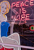 Front window of a neon sign shop with bullet hole in Albuquerque, New Mexico.