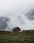Holzhütte in der nebligen Bergwelt von Norwegen