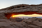 Sun shines through the Mesa Arch at sunrise.