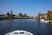 Bow of a Le Boat Horizon 4 houseboat on the River Thames with All Saints Church Tower and Marlow Suspension Bridge, Marlow, Buckinghamshire, England, United Kingdom