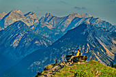 Woman hiking sits on observation bench and looks at Karwendel, from Gratlspitze, Wildschönau, Kitzbühel Alps, Tyrol, Austria