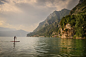 Mann fährt auf SUP am Badestrand bei Marone, Iseosee (Lago d'Iseo, auch Sebino), Brescia und Bergamo, Oberitalienische Seen, Lombardei, Italien, Europa