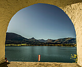 Blick durch einen Bogen auf den Wolfgangsee und die Berge des Salzkammerguts, St. Wolfgang, Österreich