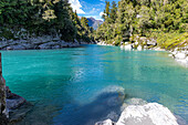 Turquoise waters flow through the Hokitika Gorge amidst lush vegetation and rock formations.