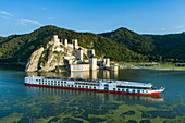 Luftaufnahme von Flusskreuzfahrtschiff Maxima (nicko cruises) auf der Donau mit der Festung Golubac in der Schlucht Eisernes Tor, Golubac, Caraș-Severin, Rumänien, Europa