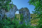 Mann beim Wandern steht auf Felsbogen Küssende Sau, Weiler im Achtal, Blaubeuren, Schwäbische Alb, Baden-Württemberg, Deutschland