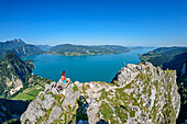 Woman hiking sitting at Schoberstein, Attersee and Mondsee in the background, from Schoberstein, Salzkammergut Mountains, Salzkammergut, Upper Austria, Austria