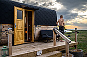 Mann auf Veranda vor Oka-Oka-Deichsauna, Ummanz, Rügen, Ostseeküste, Mecklenburg-Vorpommern, Deutschland